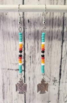 a pair of colorful beaded earrings with an elephant charm hanging from it's earwires