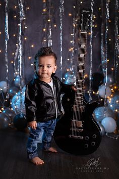 a young boy is holding an electric guitar in front of christmas lights and streamers