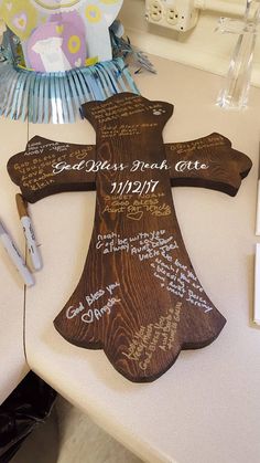 a wooden cross with writing on it sitting on a table next to some pens and paper