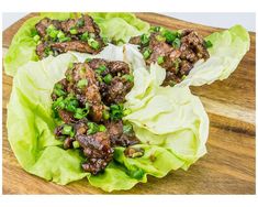 lettuce wraps with meat and green onions on a wooden cutting board, ready to be eaten