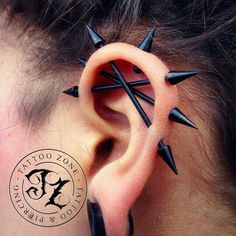 a person with black spikes on their ear and behind the ear is a pair of piercings