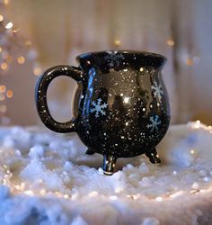 a black coffee mug sitting on top of a white cake covered in frosted stars