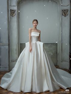 a woman in a white wedding dress standing on a wooden floor next to a wall