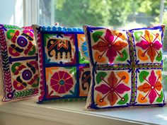 three decorative pillows sitting on top of a window sill