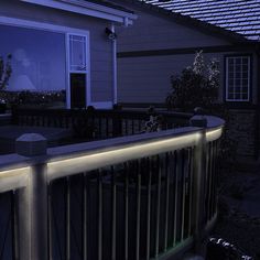 an outside view of a house at night with lights on the railing and windows lit up