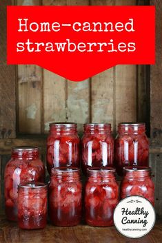 some jars filled with strawberries sitting on top of a wooden table next to a sign that says home - canned strawberries