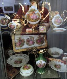 an assortment of antique china on display in a glass case