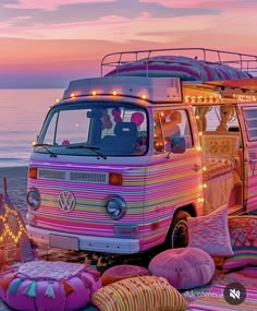 a vw bus parked on top of a beach next to pillows and rugs