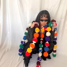 a woman sitting in front of a white backdrop with lots of balls and letters on it