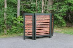 a large wooden box sitting on the side of a road in front of some trees