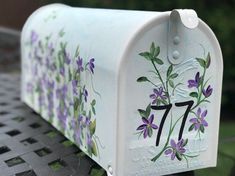 a white mailbox with purple flowers painted on it's front and the number seven