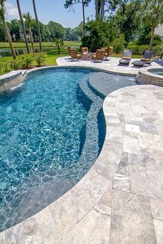 an outdoor swimming pool surrounded by palm trees and lawn chairs, with blue water in the middle