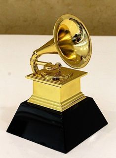 an old fashioned golden record player on top of a black base with a gold horn