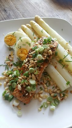 a white plate topped with fish and asparagus