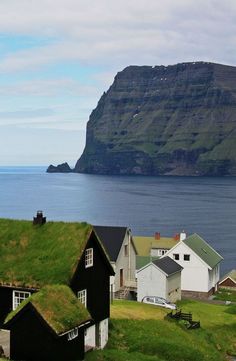 some houses with grass roofs and water in the backgrouds, near an island