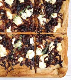 an overhead view of a square pizza with cheese and herbs on it, cut into squares