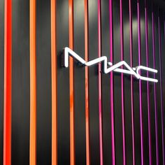 the mac logo is mounted on an orange, purple, and red wall with vertical stripes