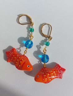 Handmade goldfish earrings. Cute, sparkly and unique. Fish is made from lightweight polymer clay and hand-painted. Beads are made from czech glass. Earrings are one of a kind :) Length from the hook: 6.4 cm / 2.52 inches. Earrings will arrive packed in cute decorative paper, so you will be able to gift them without the need for additional gift wrapping. Disinfect the hook before wearing. CARE INSTRUCTIONS:  Do not keep your earrings in direct sunlight as it may affect the metal color. Be gentle with your earrings; avoid playing with them or pulling on them. Do not bathe while wearing your earrings; keep them away from water. Keep earrings in a dry, shaded place. Keep each pair of earrings separate from each other because different types of metals can react, potentially causing changes in t Fish Clay Earrings, Goldfish Earrings, Unique Fish, Painted Beads, Fish Earrings, Beach Earrings, Le Crochet, Earrings Polymer Clay, Handmade Jewelry Gift