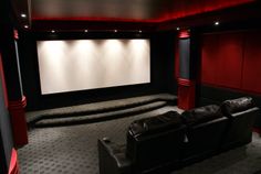 a home theater with black leather seats and red walls