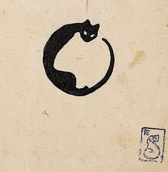 a black cat sitting on top of a piece of paper next to a rubber stamp