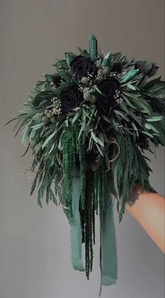 a bouquet of greenery is being held by someone's hand