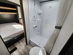 a small bathroom with a shower, toilet and bunk bed