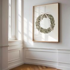 an empty room with a wreath hanging on the wall and wooden flooring in front of it