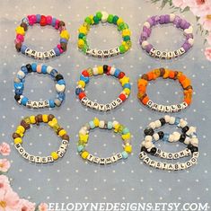 six different bracelets with words on them and flowers in front of the word nameplate