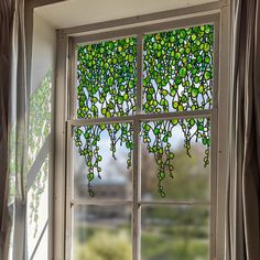 a stained glass window with vines hanging from it's sides, in front of a curtained window