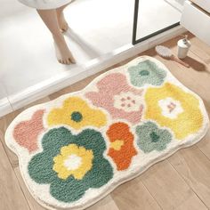 a dog is standing next to a flower rug on the floor in front of a door