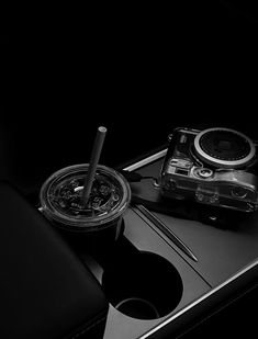 a black and white photo of a cell phone with a compass on the table next to it