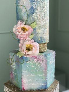 a multi - tiered cake with flowers on top is decorated in pastel colors