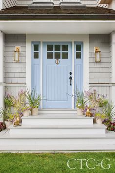 a blue front door on a white house with potted plants in the foreground