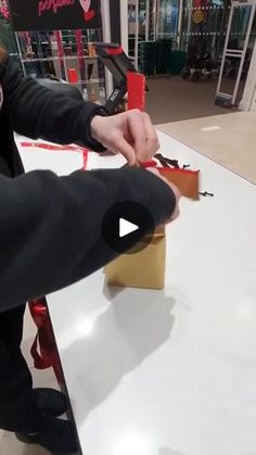 a person cutting paper with scissors on top of a white table in front of a store