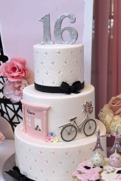 a three tiered cake decorated with pink and white flowers, paris eiffel tower in the background