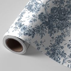 a blue and white wallpaper with floral designs on the bottom, along with a roll of tape