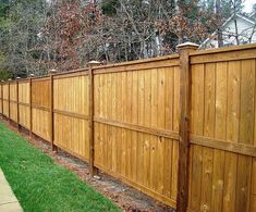 a wooden fence with grass and trees in the background