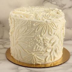 a white frosted cake sitting on top of a gold plate