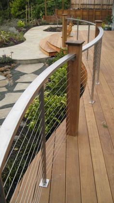 a cat sitting on top of a wooden deck next to a metal fence and planter