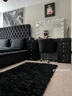 a black and white bedroom with a bed, desk, mirror and dresser in it