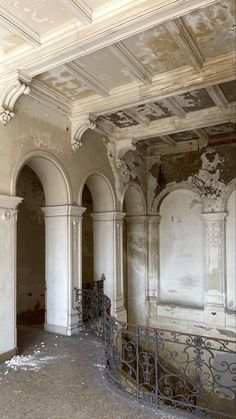 an empty room with white walls and ornate iron work on the ceiling, surrounded by columns