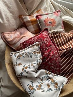 a basket filled with lots of pillows on top of a bed