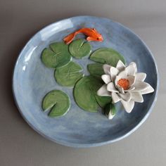 a bowl with water lilies and two orange fish in it