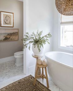 a white bath tub sitting next to a toilet in a bathroom under a light fixture