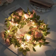 a wreath made out of fake flowers and lit up with fairy lights on the table