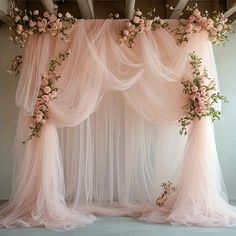 a pink wedding arch decorated with flowers and tulle