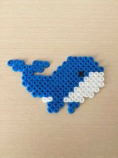 a blue and white whale made out of legos on a wooden surface with the shape of an elephant