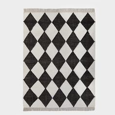 a black and white rug with diamond shapes on the bottom, in front of a gray background