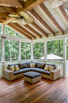 a large couch sitting on top of a wooden floor next to a ceiling mounted fan