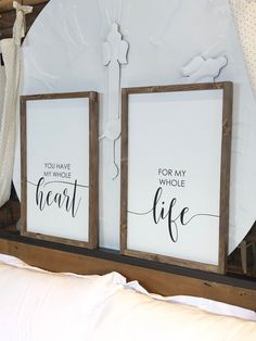 two wooden framed signs sitting on top of a bed next to a white comforter